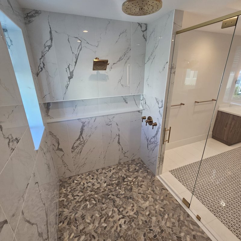 Marbled shower walls and patterned floors by Jason's Carpet & Tile